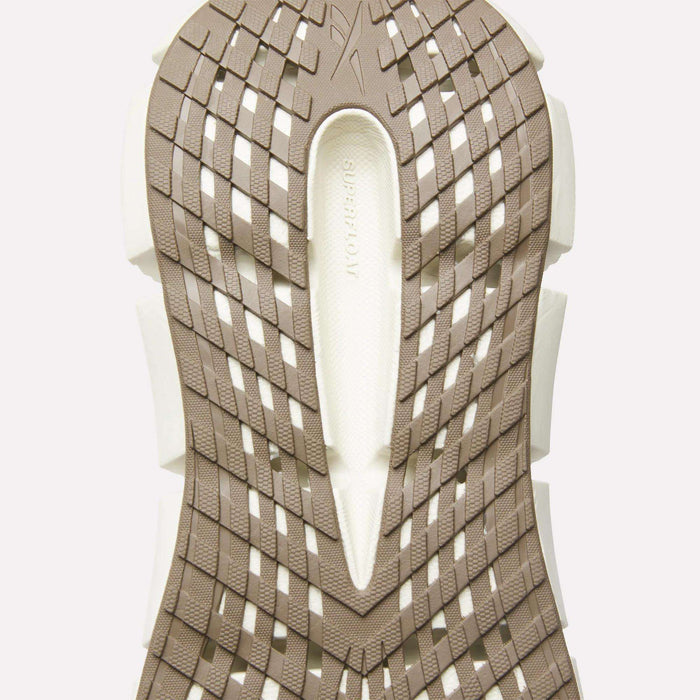 Close-up of the beige and white sole on Reebok Men's FloatZig 2 Running Shoes, showcasing a geometric crisscross tread with 'SUPERFLOW' embossed in the center, highlighting Superfloat+ cushioning for enhanced comfort.