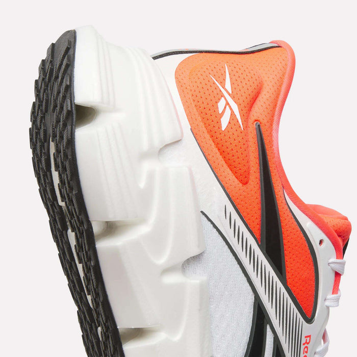 Close-up of men's Reebok FloatZig 2 Running Shoes with a supportive orange, black, and white upper featuring the Reebok logo, plus a white sole with deep grooves and black tread.