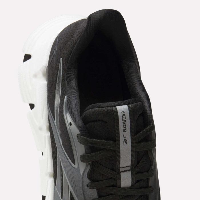 A close-up top view of Reebok Men's FloatZig 2 Running Shoes in black with white accents, featuring a chunky Superfloat+ cushioning sole, a tongue label reading "FLOATZIG" with the Reebok logo, and visible black laces.