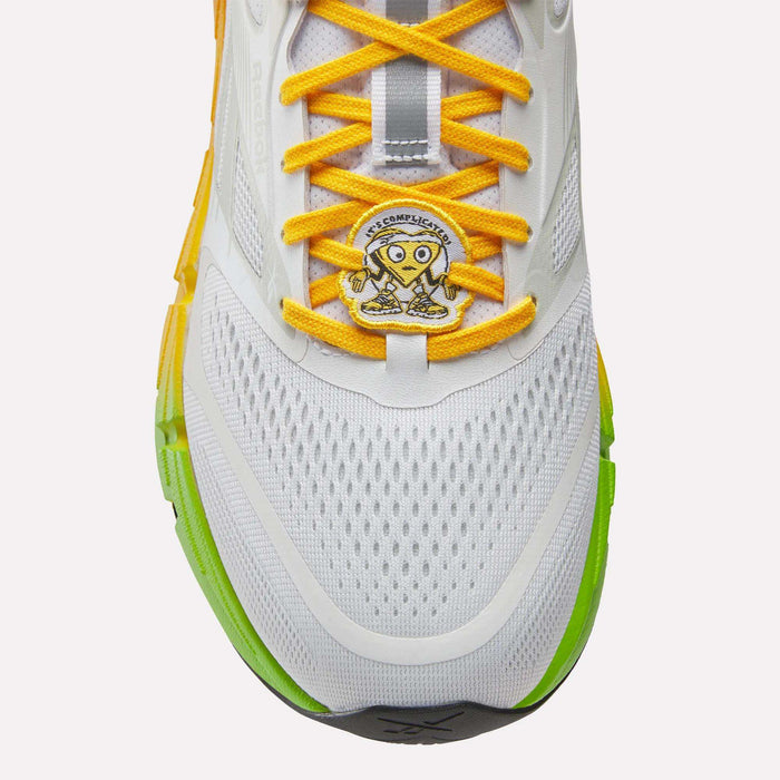 Reebok Men's FloatZig 2 SoleMates Running Shoes feature white uppers, yellow laces, a cartoon heart patch with "Act Confidently," lightweight foam midsoles, and green-yellow sole accents for comfort and style.
