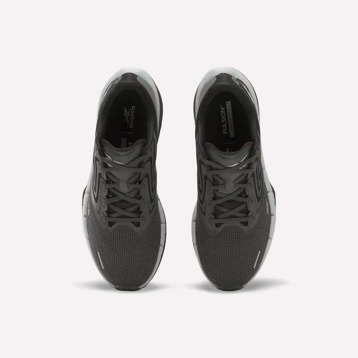 A pair of Men’s FloatZig Tread Running Shoes by Reebok in black, seen from above with laces, mesh uppers, and branded tongue. Cushioned midsoles make them ideal for treadmill workouts. Placed side by side on a plain white background.