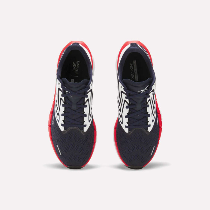 The Reebok Men's FloatZig Tread Running Shoes feature navy blue mesh toes, white patterned sides, and bright red soles—ideal for treadmill workouts. Shown from above against a plain white background.
