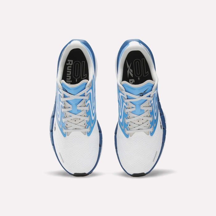 Top view of Reebok Men's FloatZig Tread Running Shoes in white with blue accents, dual-density midsole, blue soles, white laces, and black insoles marked "Running," placed side by side on a light background.