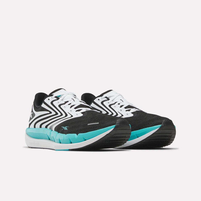 The Reebok Men's FloatZig Tread Running Shoes feature a black and white zigzag pattern, teal blue accents, cushioned midsole, white laces, and thick white soles with a teal toe section. Ideal for treadmill workouts. Shown on a plain white background.