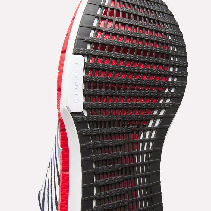Close-up of the black, grid-patterned rubber outsole on Reebok Men's FloatZig Tread Running Shoes, accented in red, white, and navy blue, with a visible GRIPTONNER label—designed for optimal treadmill workouts.