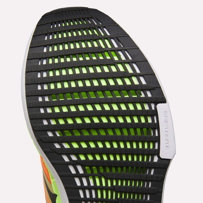Close-up of the Reebok Men's FloatZig Tread Running Shoes sole, showing a black and white tread with horizontal grooves, green accents under the outsole, a cushioned midsole, and "GRIPTONITE" embossed on one section.