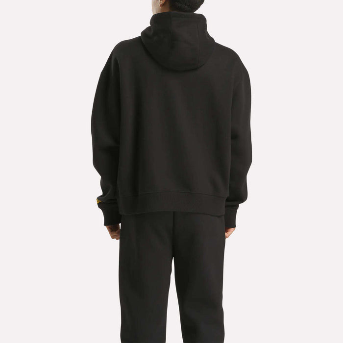 A person stands with their back to the camera, wearing a Men's Hoodie by Reebok in black, paired with matching black pants against a plain white background.