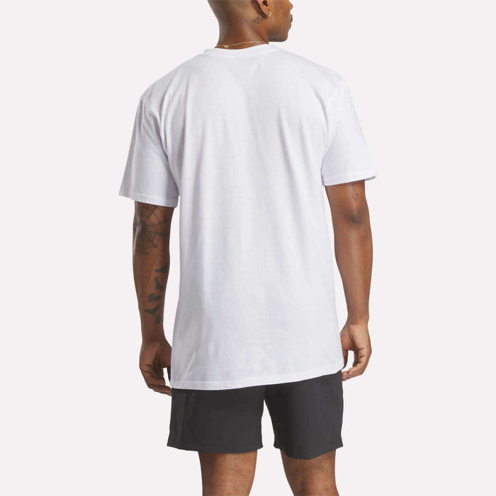 A person is seen from the back wearing a relaxed fit Reebok Men's Identity Small Logo T-Shirt and black shorts, standing against a light background.