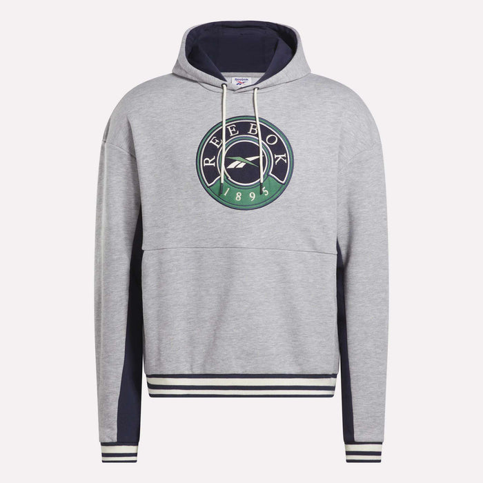 The Men's Lawn Club French Terry Hoodie by Reebok is a light gray cotton-blend hoodie with a navy hood lining, striped cuffs and hem, front pocket, and features a round black, green, and white Reebok 1895 logo on the chest.