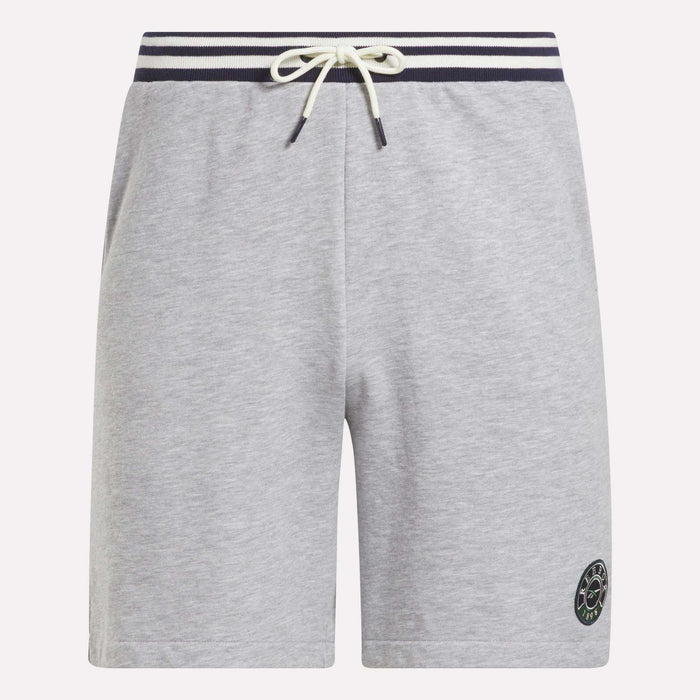 The Reebok Men's Lawn Club Shorts are light gray with a navy and white striped elastic waistband, white drawstring, side pockets, and a small circular logo on the lower left leg. Made from a comfortable cotton blend.