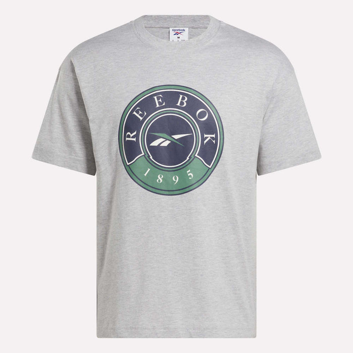 The Men's Lawn Club T-Shirt by Reebok is a light gray cotton tee with a large circular green and dark blue Lawn Club logo featuring "REEBOK 1895" and the Reebok symbol on the front.