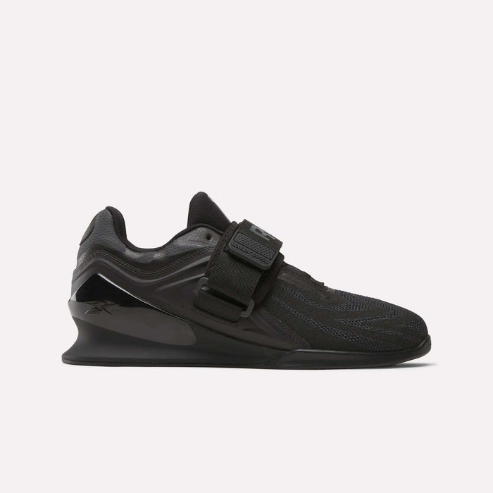 The Reebok Men's Legacy Lifter IV Shoes feature a black textured mesh upper, thick sole, and wide midfoot strap for added stability, displayed in side profile against a plain white background.
