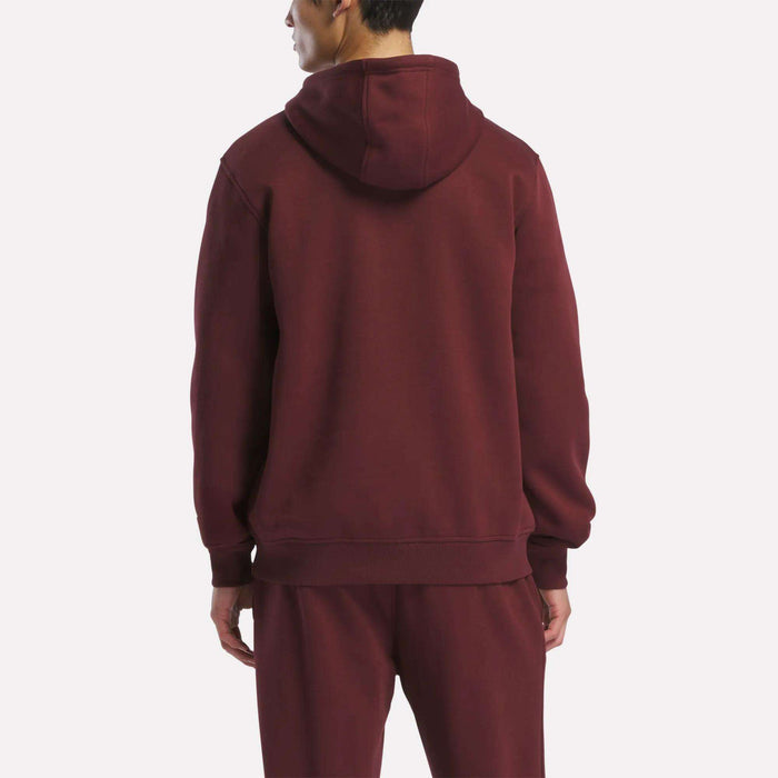 A person stands with their back to the camera, displaying the Reebok Men's Logo Hoodie and matching pants in maroon fleece against a plain light background.