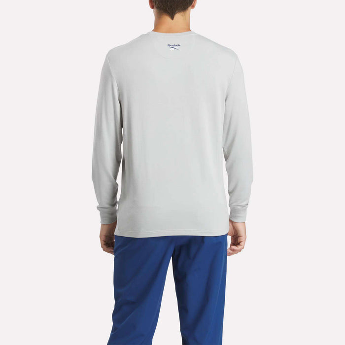 A person faces away from the camera, wearing the Reebok Men's Long Sleeve Golf Sweatshirt in light gray with UPF 30+ protection and blue pants, set against a plain white background.