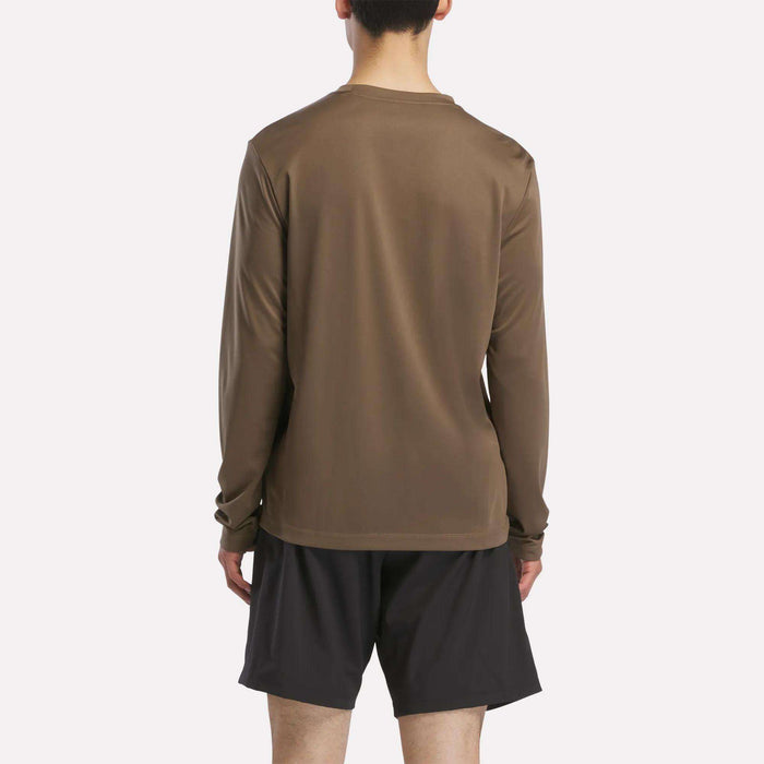 A person stands with their back to the camera in a Reebok Men's Long Sleeve Tech T-Shirt and black shorts against a plain light background—perfect for keeping warm during cold weather workouts.