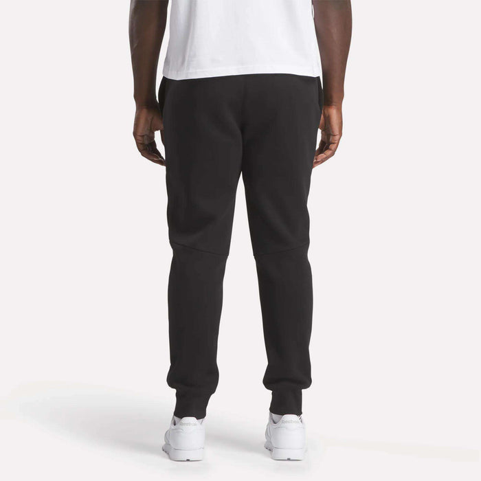 A man wearing Reebok Men's Motion Joggers in black and a white shirt.