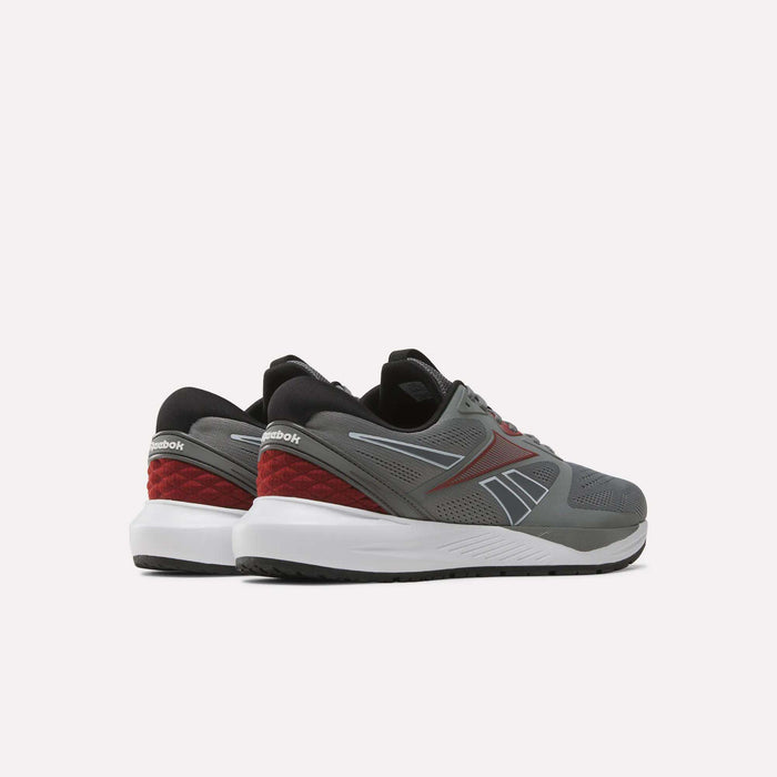 A pair of Reebok Men's Nanoflex 2 Training Shoes in gray with black, red, and white accents are displayed on a plain white background, shown from the back and side angles. These shoes feature a breathable mesh upper designed to provide enhanced comfort during intense training sessions.