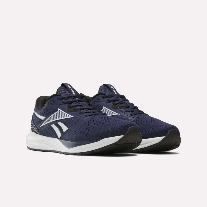 A pair of Reebok Men's Nanoflex Trainer 2 Shoes in navy blue with white soles and white and gray accents is displayed on a plain white background.