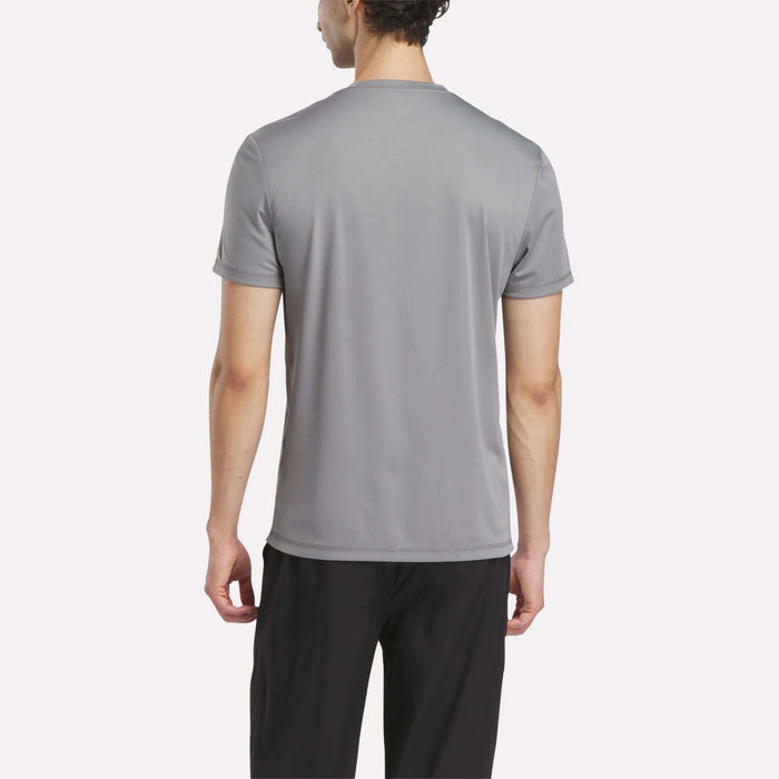 A man stands facing away, wearing a short-sleeved gray Men's Reebok x F45 Training T-Shirt and black pants against a plain white background.