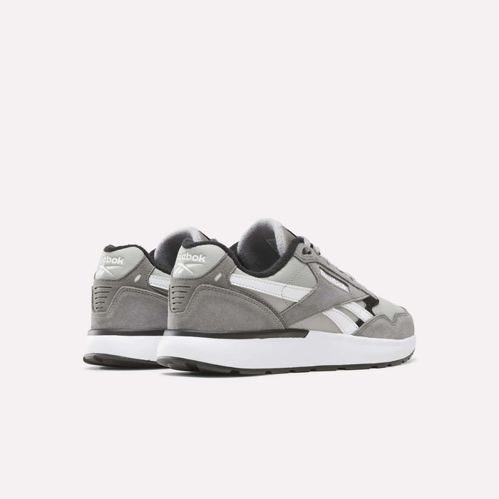 A pair of Reebok Men’s Run LXS Shoes in gray and white rest on a white background, with one shoe facing forward and the other angled to display the heel and side logo. Crafted from full-grain leather, these retro-inspired running shoes combine classic style with lasting durability.