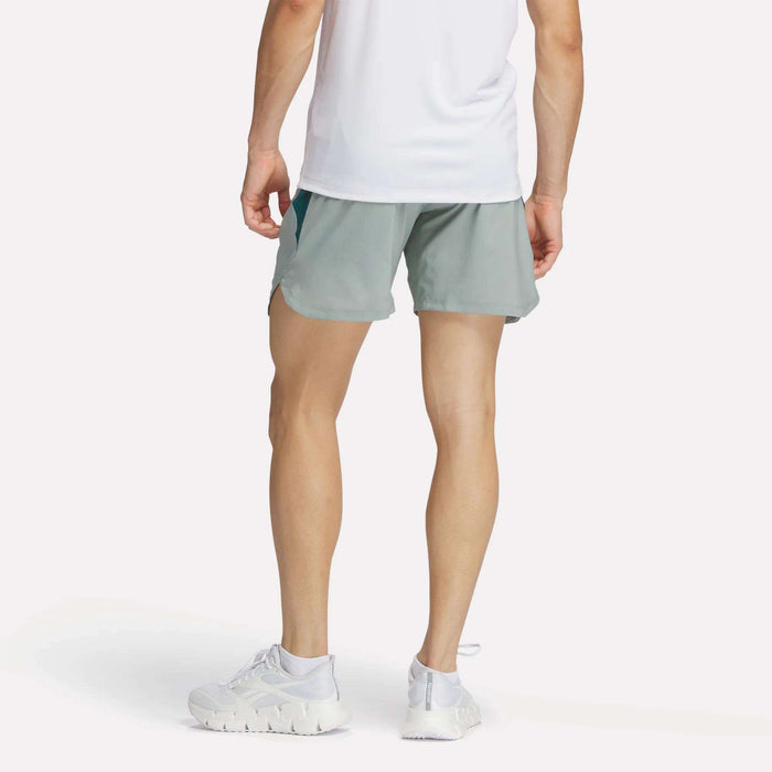 A man wearing Reebok Men's Run Shorts with inner tights and a white tank top.