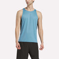 A man wears a Reebok Men's Run Speedwick Singlet and black shorts, standing against a plain white background.