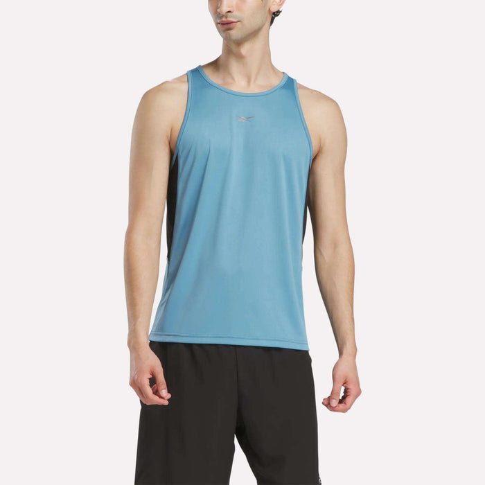A man wears a Reebok Men's Run Speedwick Singlet and black shorts, standing against a plain white background.