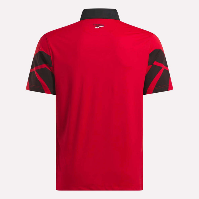 Back view of the Reebok Men's Signature Vector Colorblocked Polo Shirt in red, featuring short sleeves, a black collar, black geometric sleeve patterns, moisture-wicking fabric, and UPF 30+ protection.