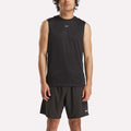 A man stands facing forward against a white background, wearing Reebok's Men's Train Sleeveless Tech Tee and black shorts, both with a small white Reebok logo that highlights their lightweight polyester construction.