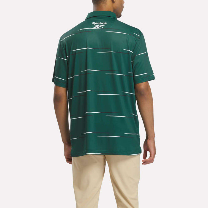 A person seen from behind wears a green Reebok Men's Tournament Polo Shirt with white horizontal stripes and beige pants.