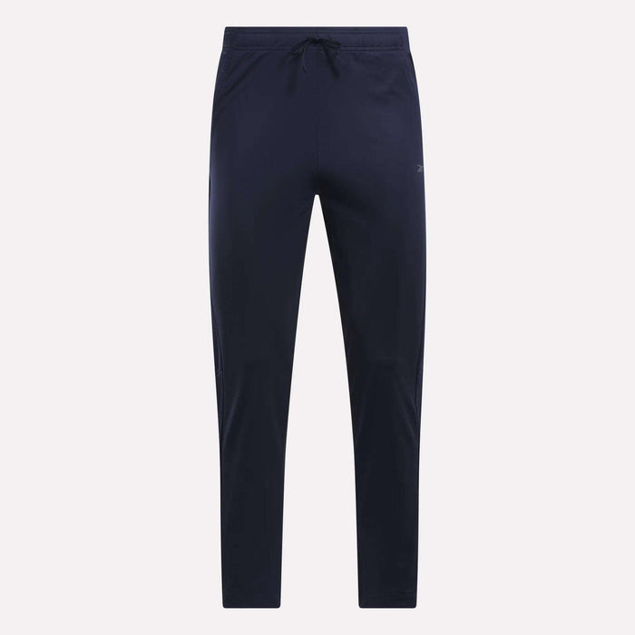 Reebok Men's Train Knit Pants in navy blue, featuring a slim fit jogger style with an elastic waistband and drawstring. Displayed against a plain light background, these gym pants have no visible logos or patterns.