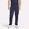 A person stands facing forward against a plain light background, wearing Reebok Men's Train Woven Unlined Pants in navy blue with a matching t-shirt and white athletic shoes. The person's head is not visible in the image.