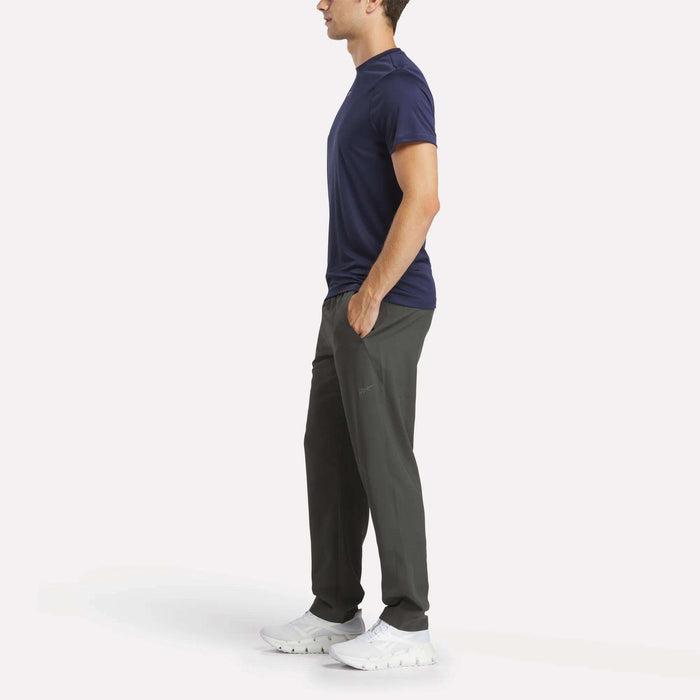 A man in a blue shirt and Reebok Men's Train Woven Unlined Pants.