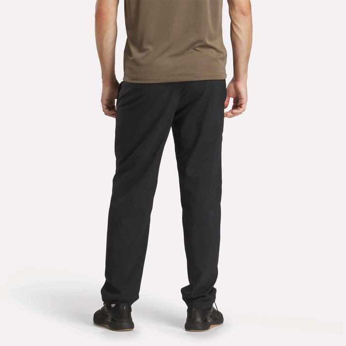 A man wearing Reebok Men's Train Woven Unlined Pants in black.