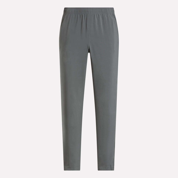 The Reebok Men's Train Woven Unlined Pants in plain gray feature an elastic waistband and are perfect as lightweight workout pants for the gym or everyday comfort, shown here against a light background.