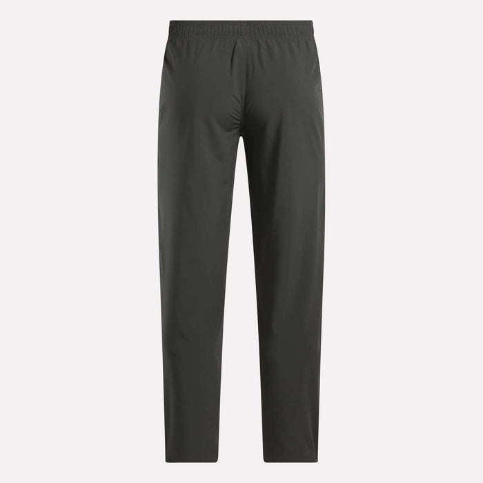Reebok Men's Train Woven Unlined Pants in dark gray feature a straight-leg design and elastic waistband, ideal as lightweight workout or gym pants. Shown against a light background.