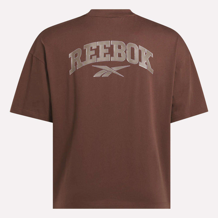 A brown Men's Varsity T-Shirt by Reebok, seen from the back, showcases an athletic look with large metallic REEBOK branding and logo boldly printed across the upper back.