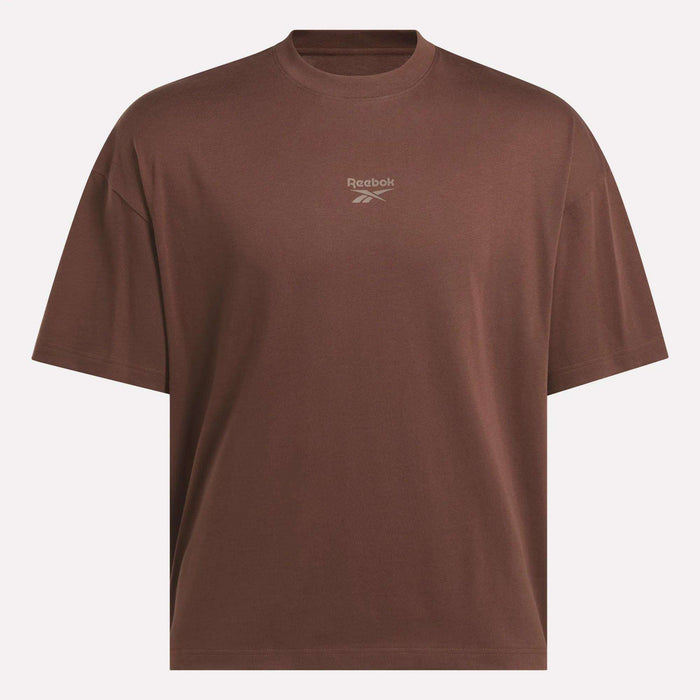 The Reebok Men's Varsity T-Shirt is an oversized brown tee with short sleeves, a crew neckline, and a small white logo and text centered on the chest—offering a casual, athletic style ideal for everyday wear.