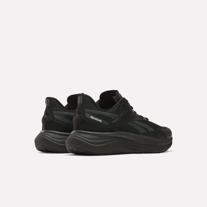 The Reebok Men's Viva Speed Shoes, shown from a rear side angle on a white background, feature black mesh uppers and thick wavy soles, delivering a perfect mix of breathability and cushioned comfort.