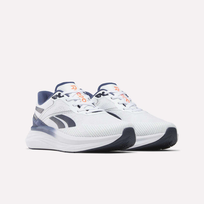 A pair of Reebok Men's Viva Speed Shoes in white, featuring navy blue accents, orange logo details, and thick cushioned soles for breathability, displayed on a plain light background.