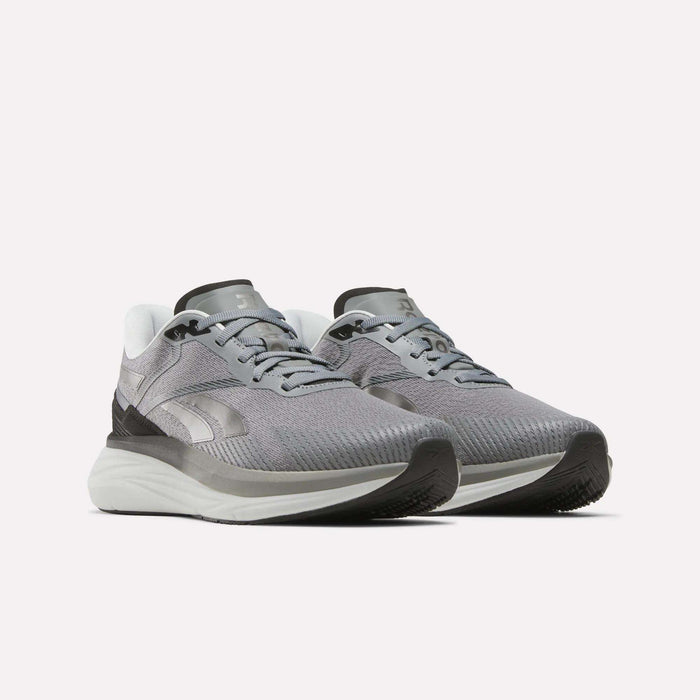 A pair of Reebok Men's Viva Speed Shoes in gray and white, featuring mesh uppers, cushioned white soles, and black accents, are displayed on a plain white background. These breathable shoes offer enhanced comfort with their cushioned soles, making them ideal for athletic activities.