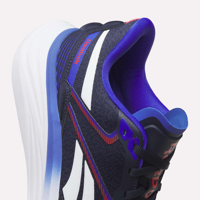 Close-up of the Reebok Men's Viva Speed Shoes in dark blue with white and red accents, featuring a thick white sole and purple inner lining. These cushioned shoes deliver superior comfort and support for active lifestyles.