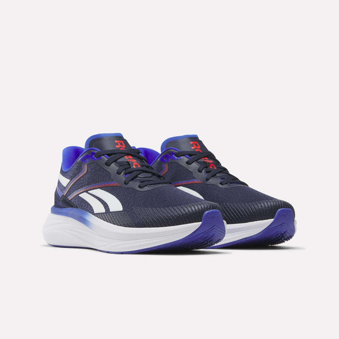 A pair of Men's Viva Speed Shoes by Reebok in navy blue, featuring white midsoles, purple accents, and white side stripes. These cushioned shoes provide comfort during daily runs and are designed with red R logos on the tongues and a textured toe area.