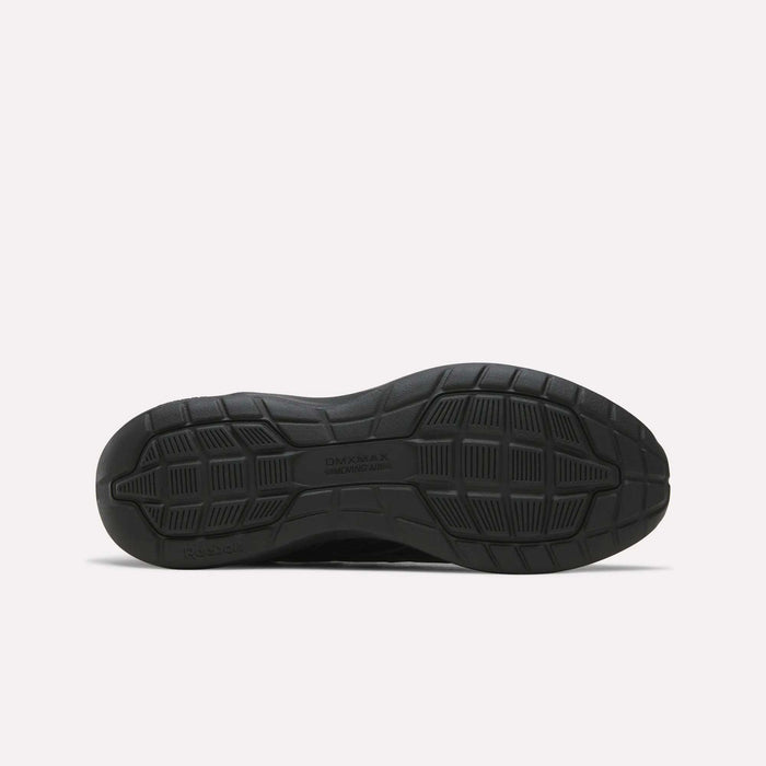 The image displays the black rubber sole of the Reebok Men's Walk Ultra 7 DMX Max Shoes, positioned flat to showcase its tread pattern. The sole includes textured grip sections and features DMX MAX and Reebok embossed on it, emphasizing the advanced DMX cushioning technology characteristic of these cushioned walking shoes.