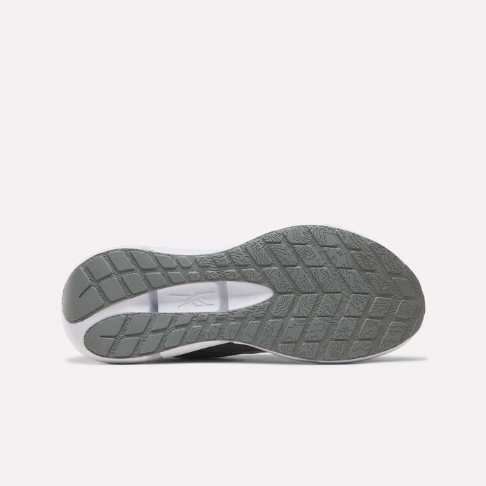 The image displays the gray treaded outsole of the Reebok Men’s Zignition Running Shoes, viewed from below against a plain white background. The sole features a wider forefoot area with a textured grip pattern and showcases the Reebok logo at the midfoot.