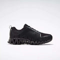 The Reebok Men's ZigWild Trail 6 Shoes, shown in profile against a white background, feature a black design with a textured geometric pattern and a thick wavy sole for enhanced cushioning.