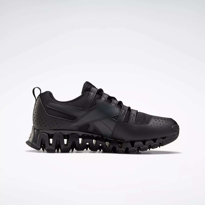 The Reebok Men's ZigWild Trail 6 Shoes is a black athletic sneaker with a wavy, textured sole, enhanced cushioning, perforated heel details, and black laces. Shown in side profile on a plain light background.