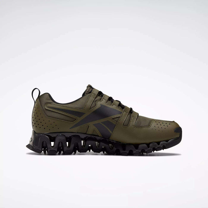The Reebok Men's ZigWild Trail 6 Shoes are olive green sneakers with black accents, a rugged wave-like sole, perforated details, enhanced cushioning, and a low-cut design, shown from the side on a plain background.