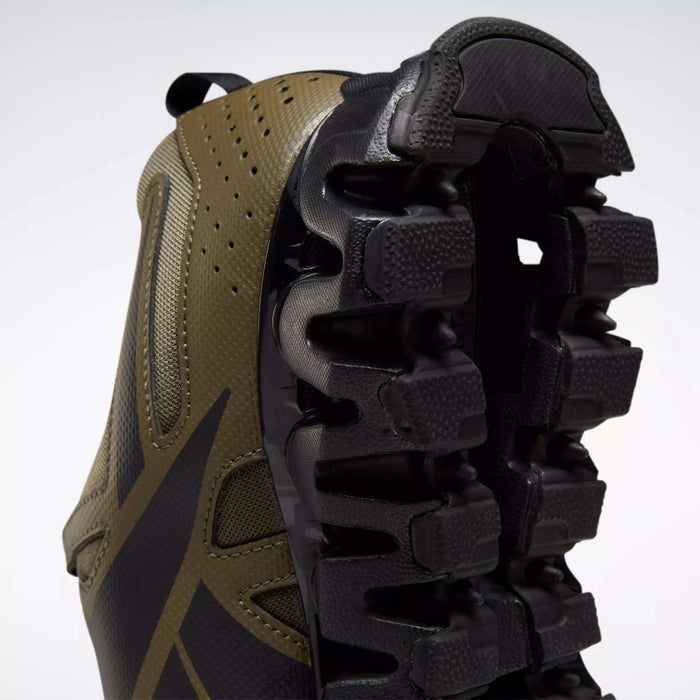 Close-up of the Reebok Men's ZigWild Trail 6 Shoes, showcasing a brown and black design with a chunky, trail-inspired black sole featuring enhanced cushioning and deep grooves, set against a plain white background.