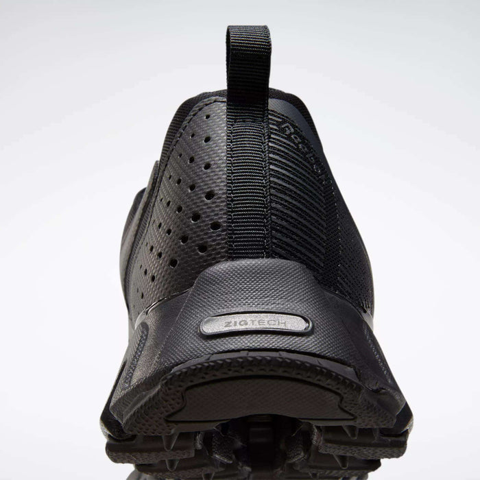 Close-up rear view of Reebok Men's ZigWild Trail 6 Shoes in black, featuring perforated sides, a textured heel, pull tab, enhanced cushioning, and a ZigTech label above the sole.